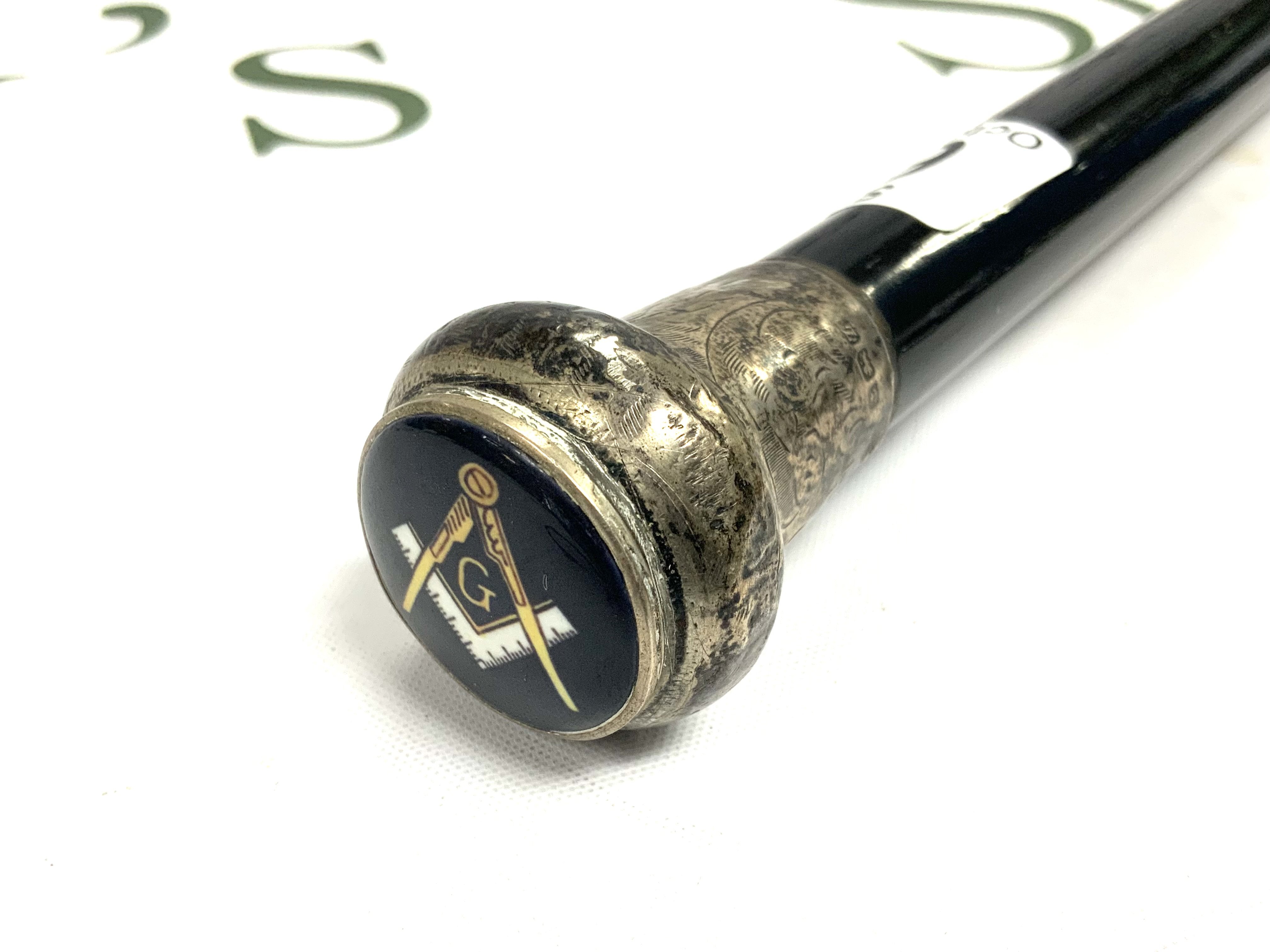 A Silver topped ebonized cane with enamelled Masonic symbol inset int he silver top. 92cm