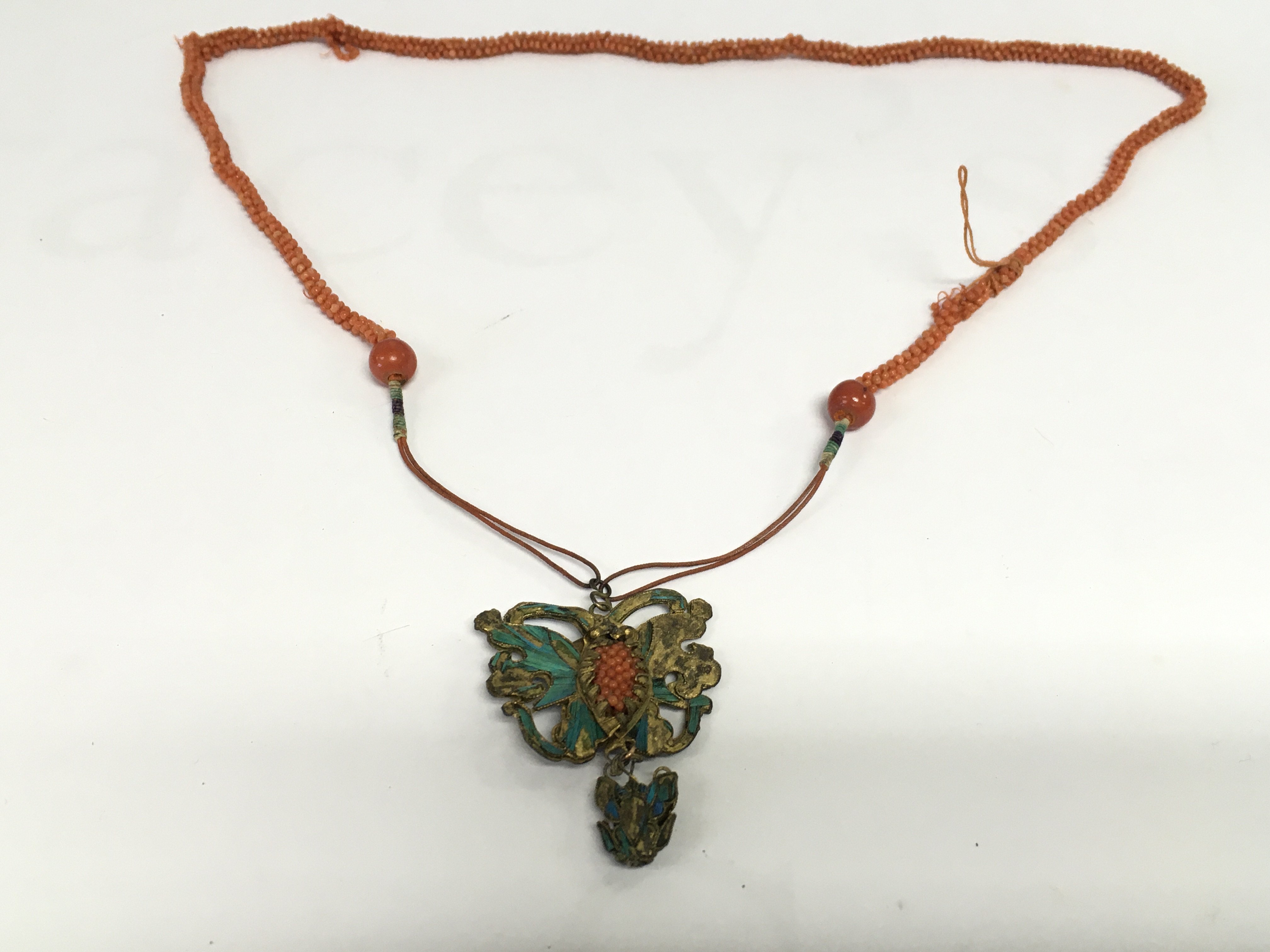 A coral necklace with a butterfly style brass pendant