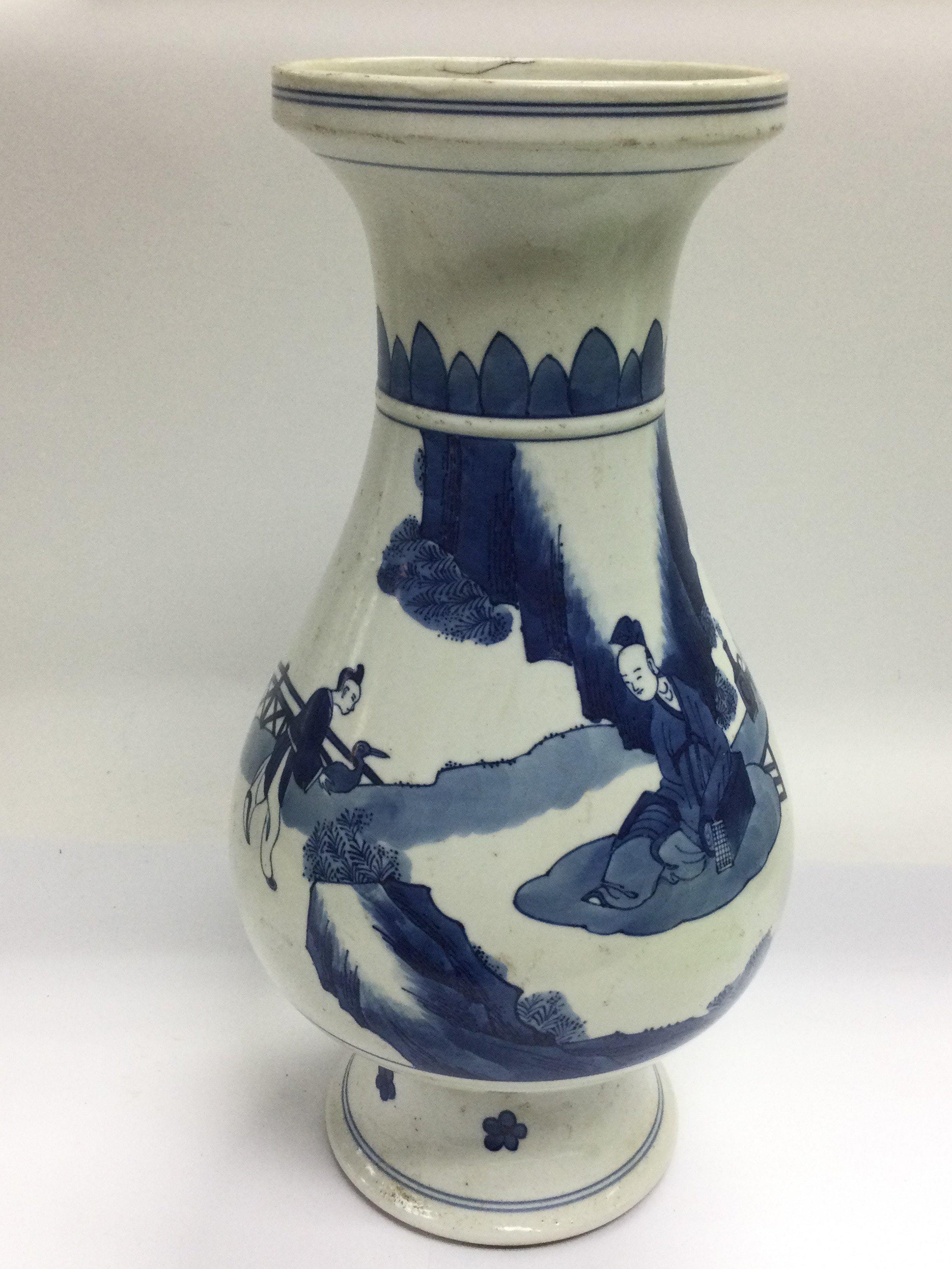 A blue and white vase decorated with figures in a garden setting approximately 35cm