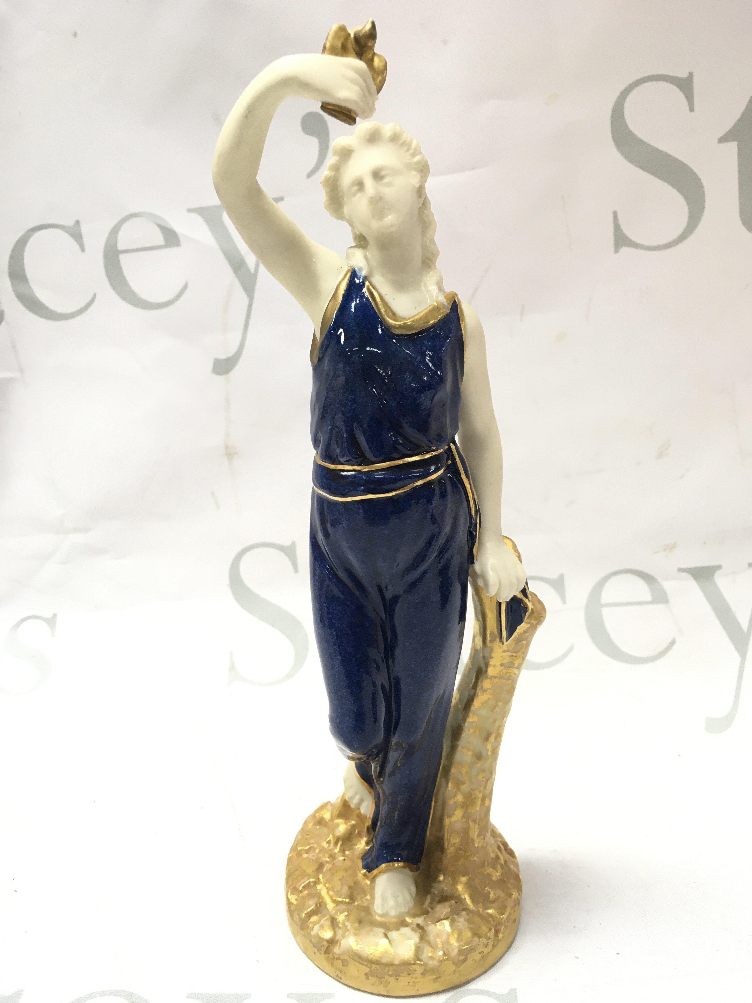 A Royal Worcester figure of Liberty standing wearing blue powdered dress edged in gilt standing on a rocky circular base , 24cm tall. This lot cannot be posted