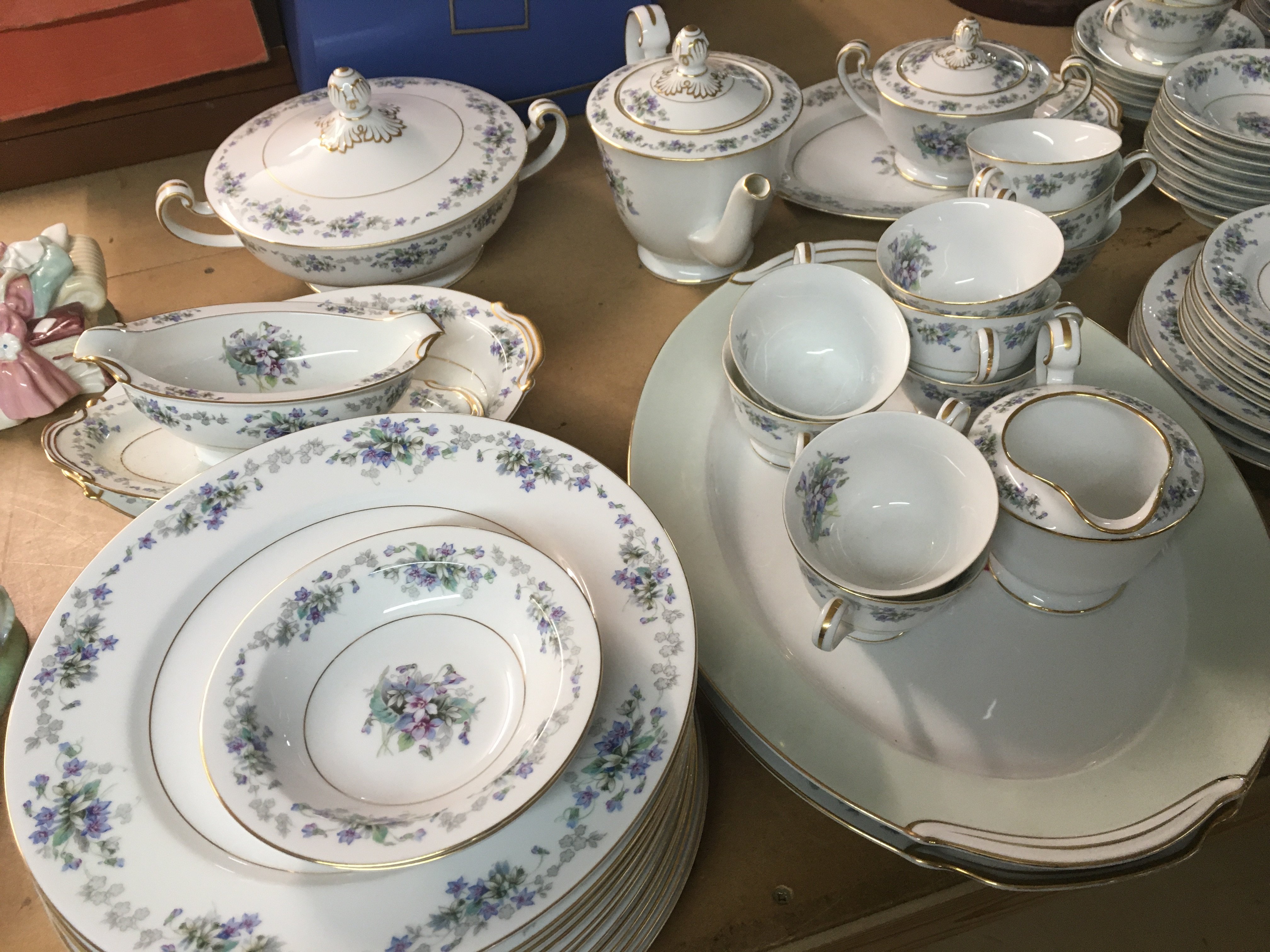 A Noritake Dinner/ tea set decorated with flowers and foliage included plates tureans teapots and plates .