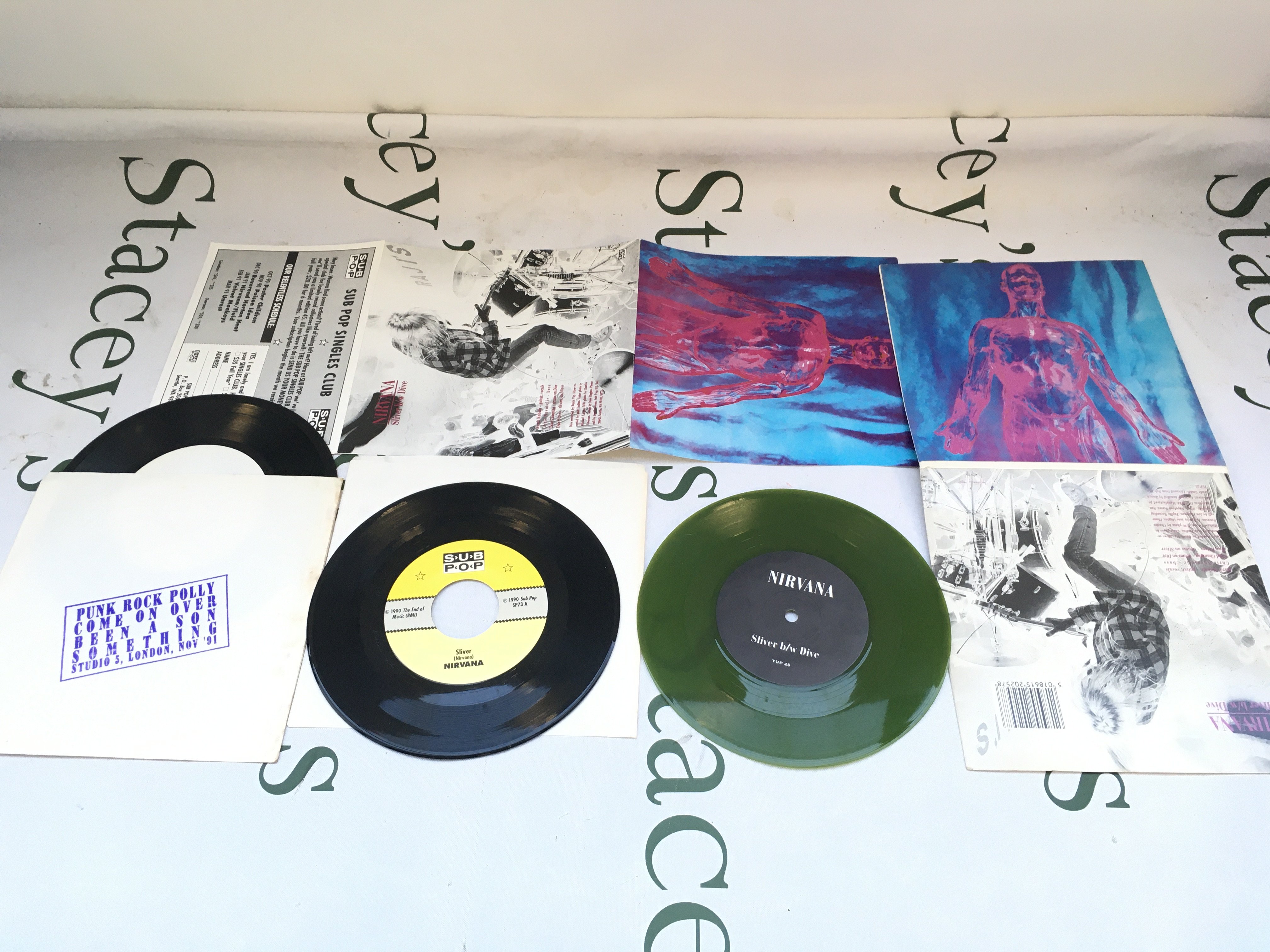 A 1990 Sub Pop pressing of Sliver / Dive by Nirvana plus a later green vinyl pressing in a gatefold sleeve plus Smells Like Nirvana EP and The Triple Platinum EP. All EX/EX.