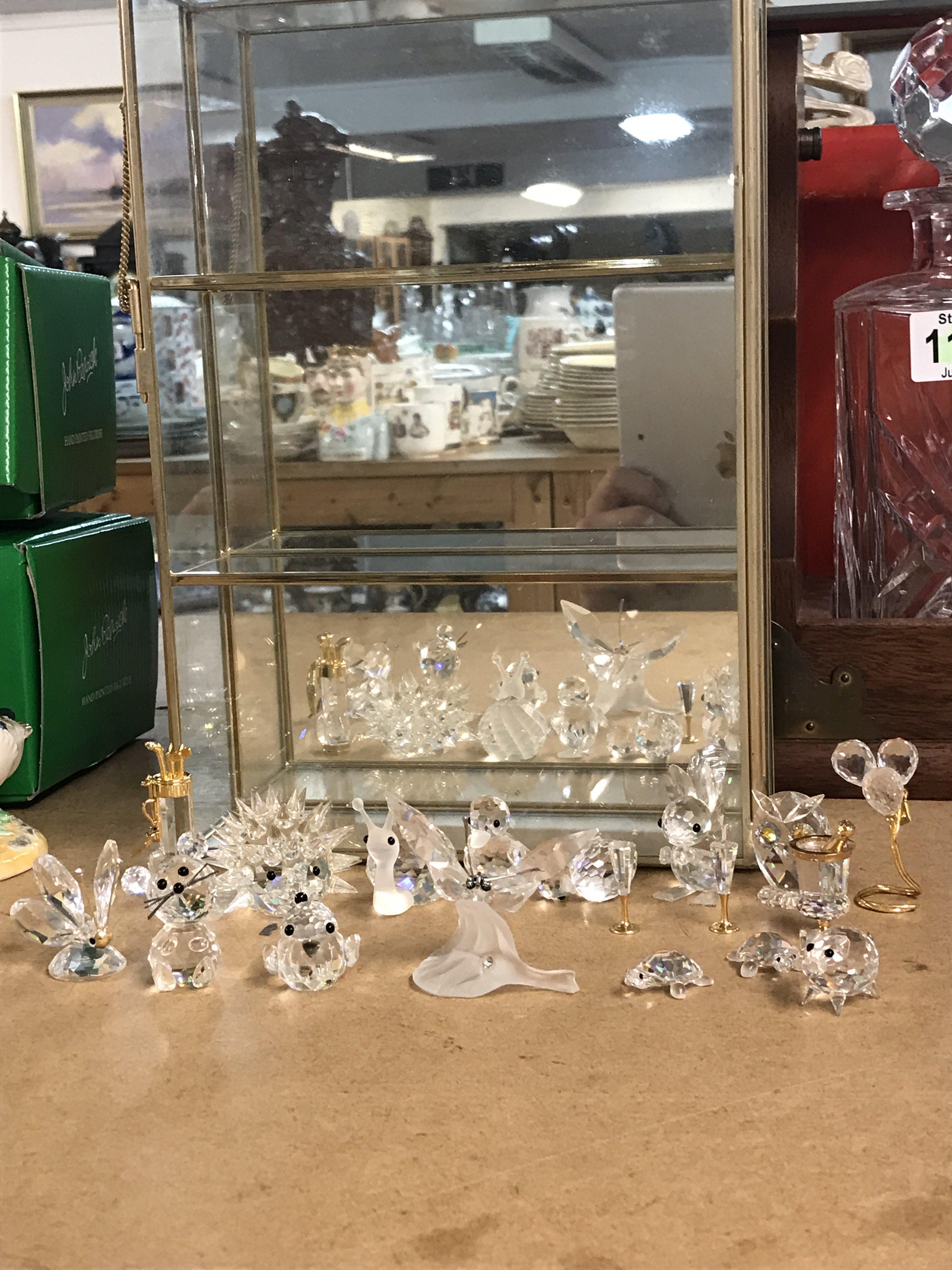 A collection of Swarovski figures and a display case. This lot cannot be posted