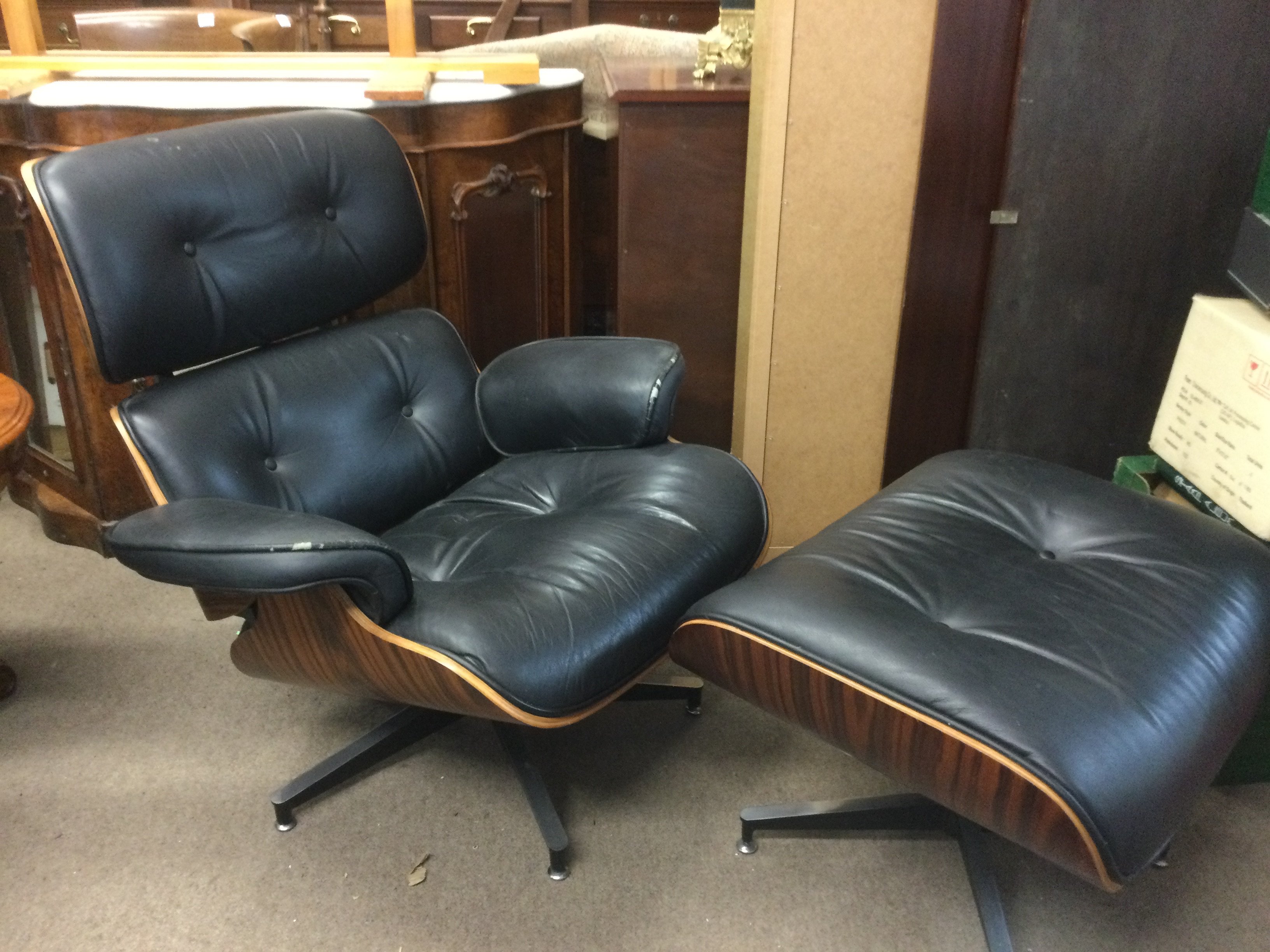 An Eames style black leather chair and footstool (2). Shipping category D.