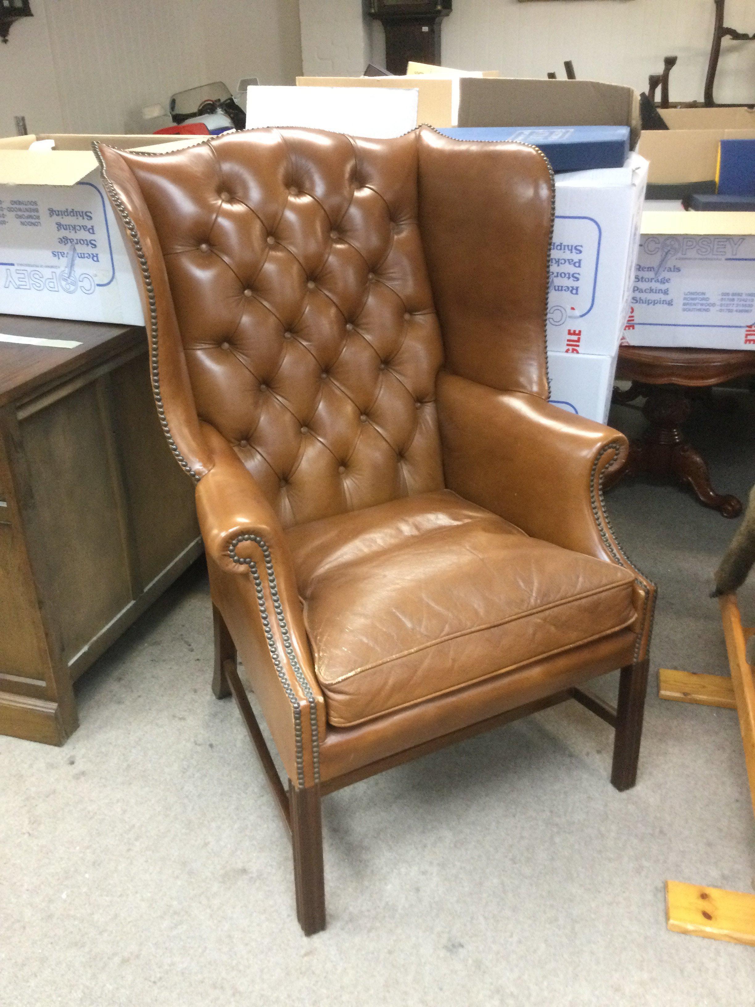 A leather button back wing armchair. Shipping category D.