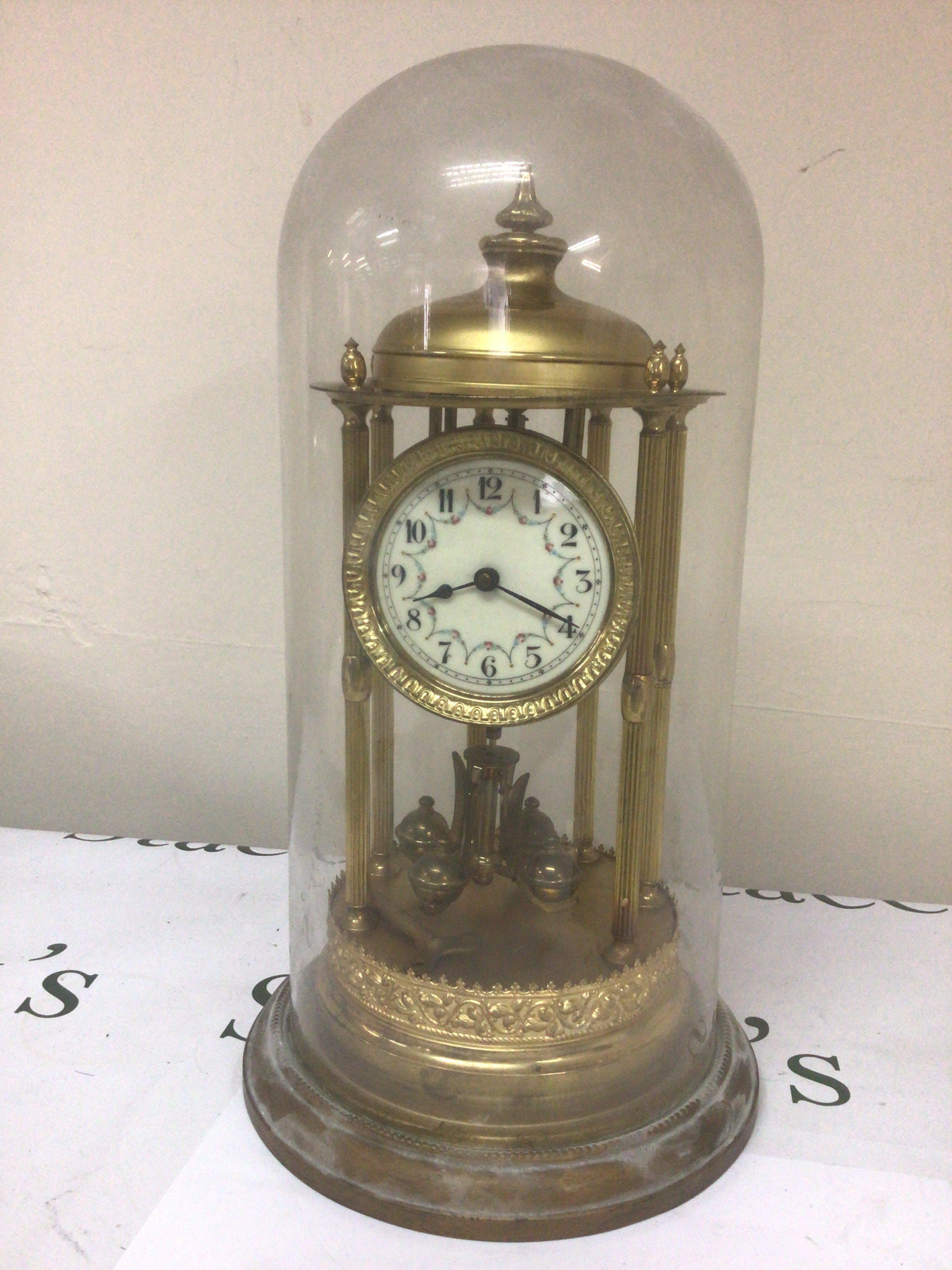 A vintage clock with six pillars an anniversary clock under a glass dome seen working. Height 45cm heigh.