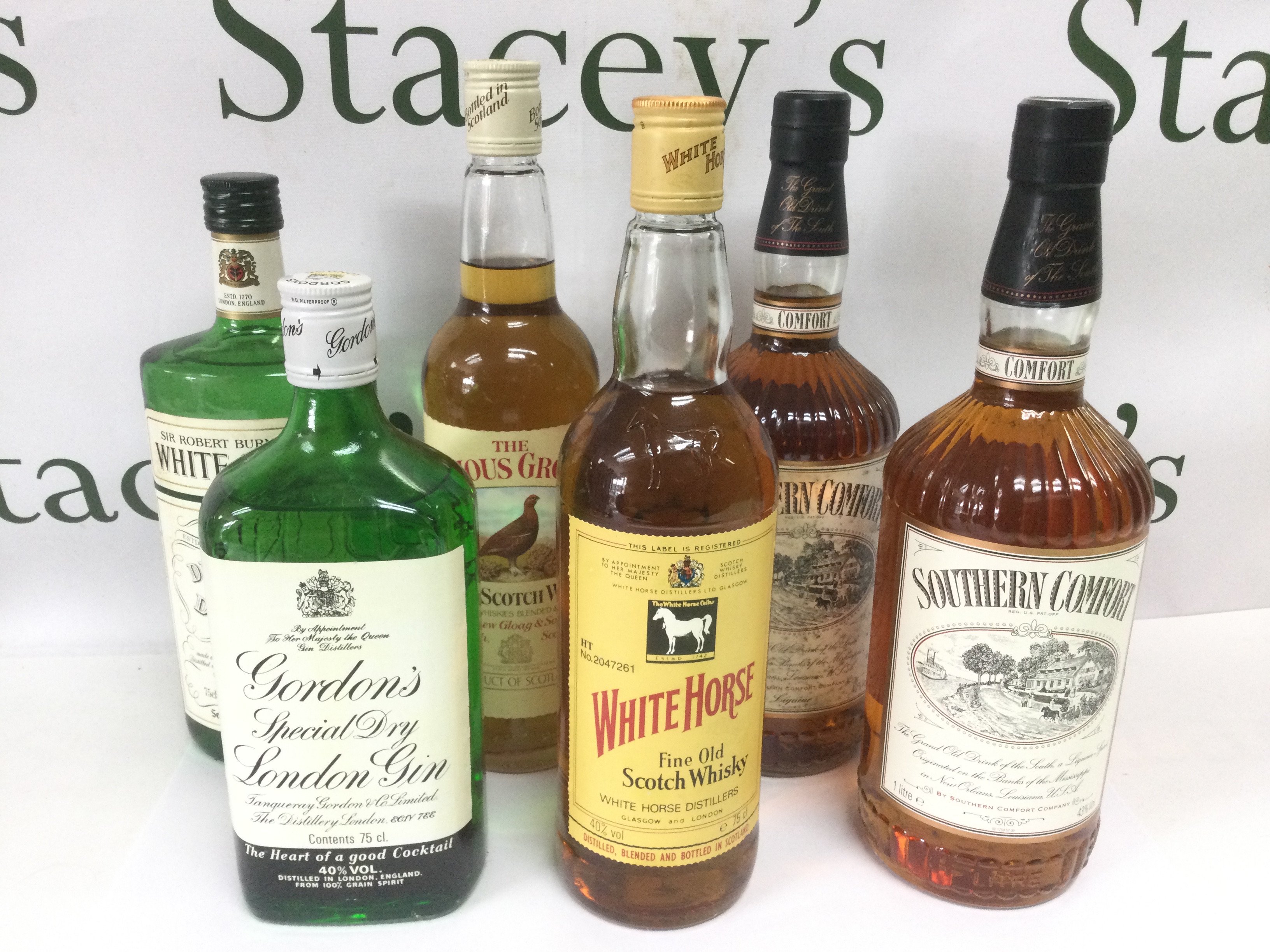 Six bottles of Whiskey and gin comprising two 1 litre bottles of Southern Comfort, Gordon's Gin etc. Shipping category D.