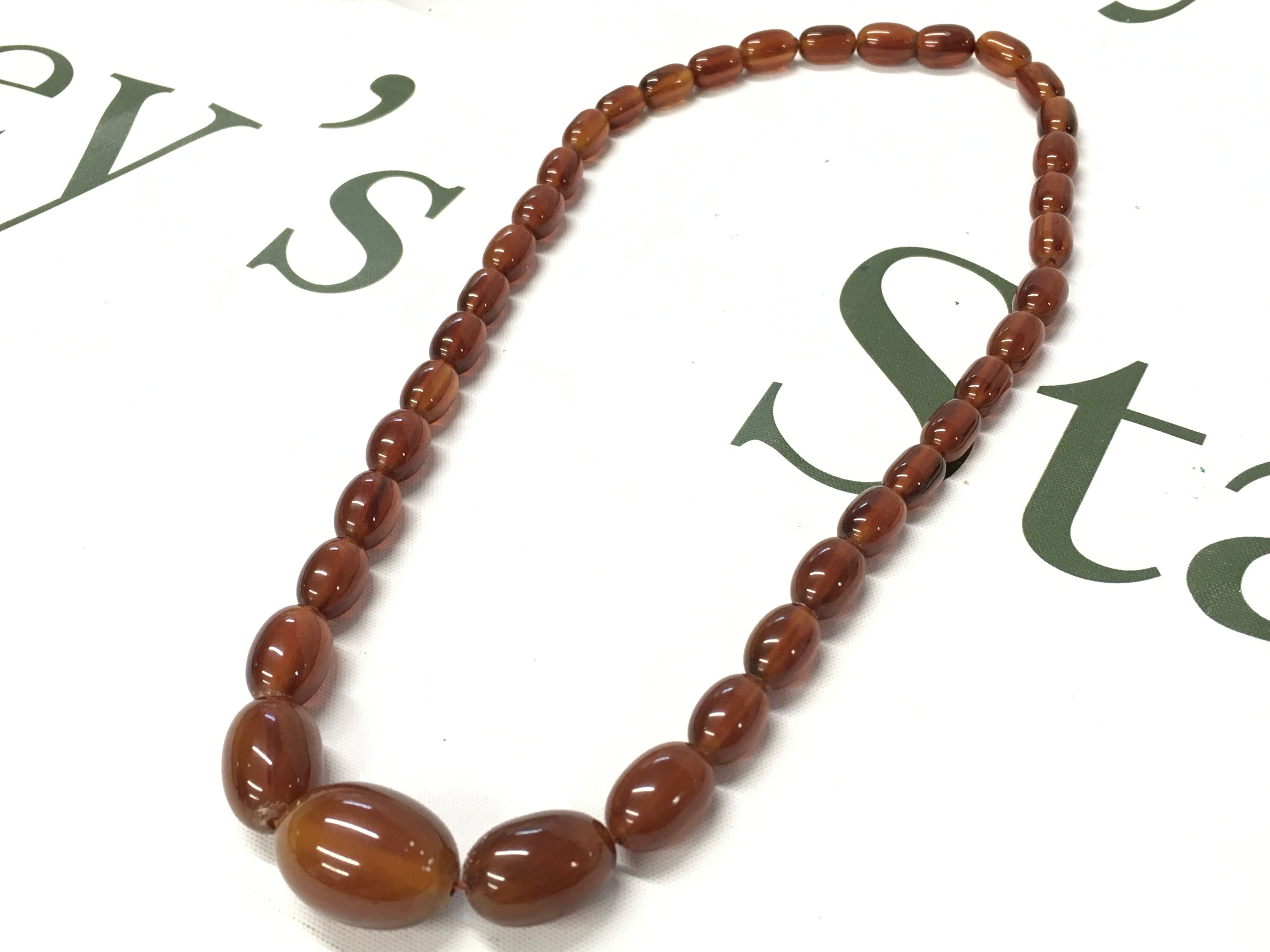 A graduated bakelite amber necklace , 54cm long. 35g total weight. Postage category A