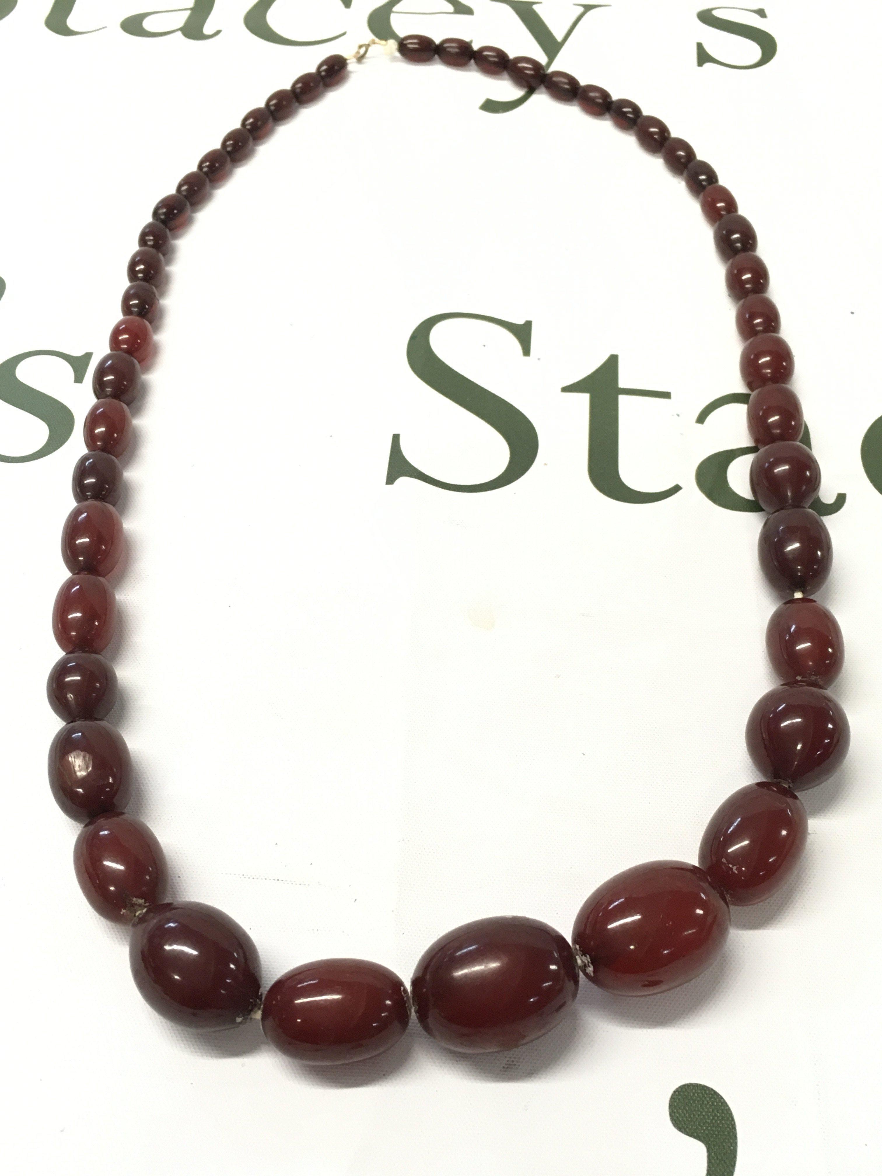 A cherry amber bakelite necklace , 80cm long. 95g total weight approximately . postage category A