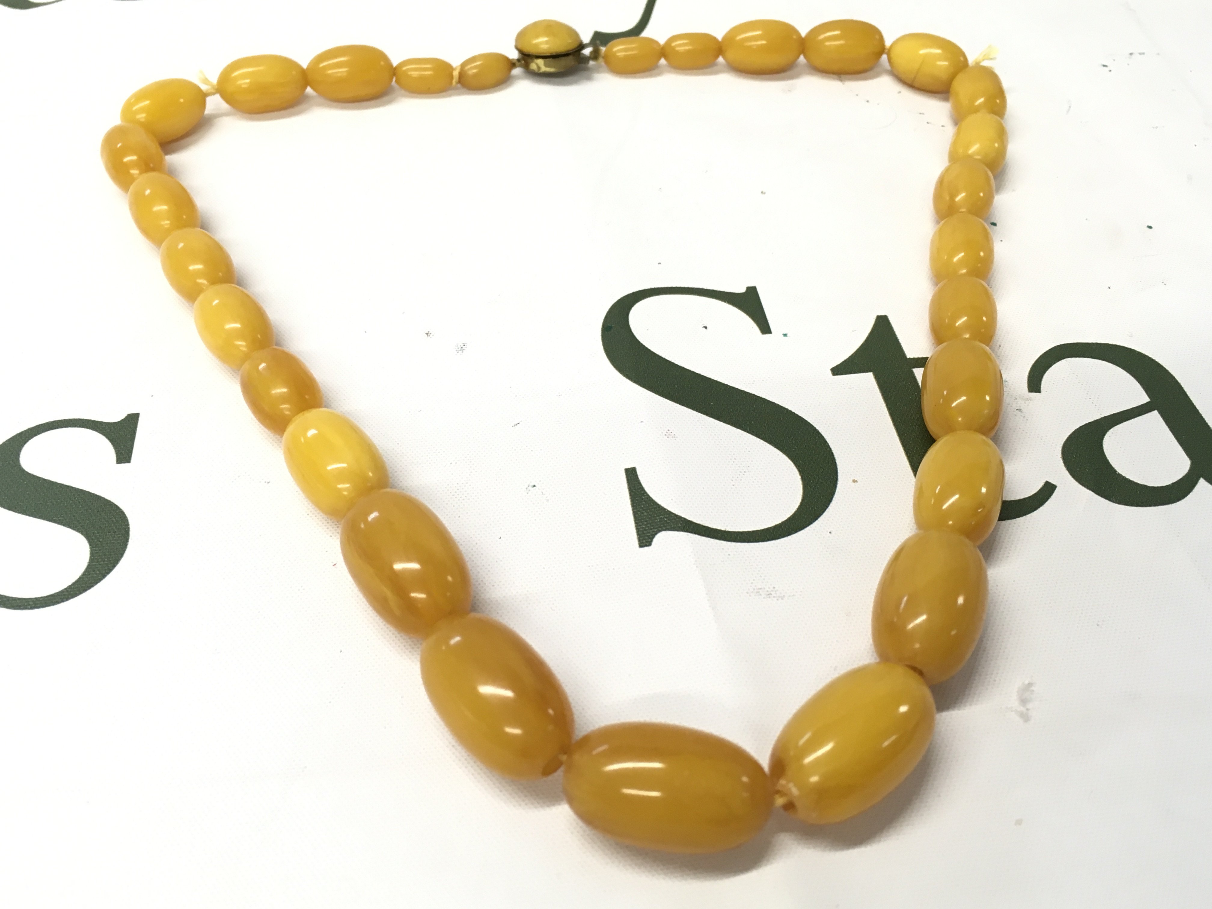 A bakelite amber necklace, 60cm long , 71g total weight. Postage category A