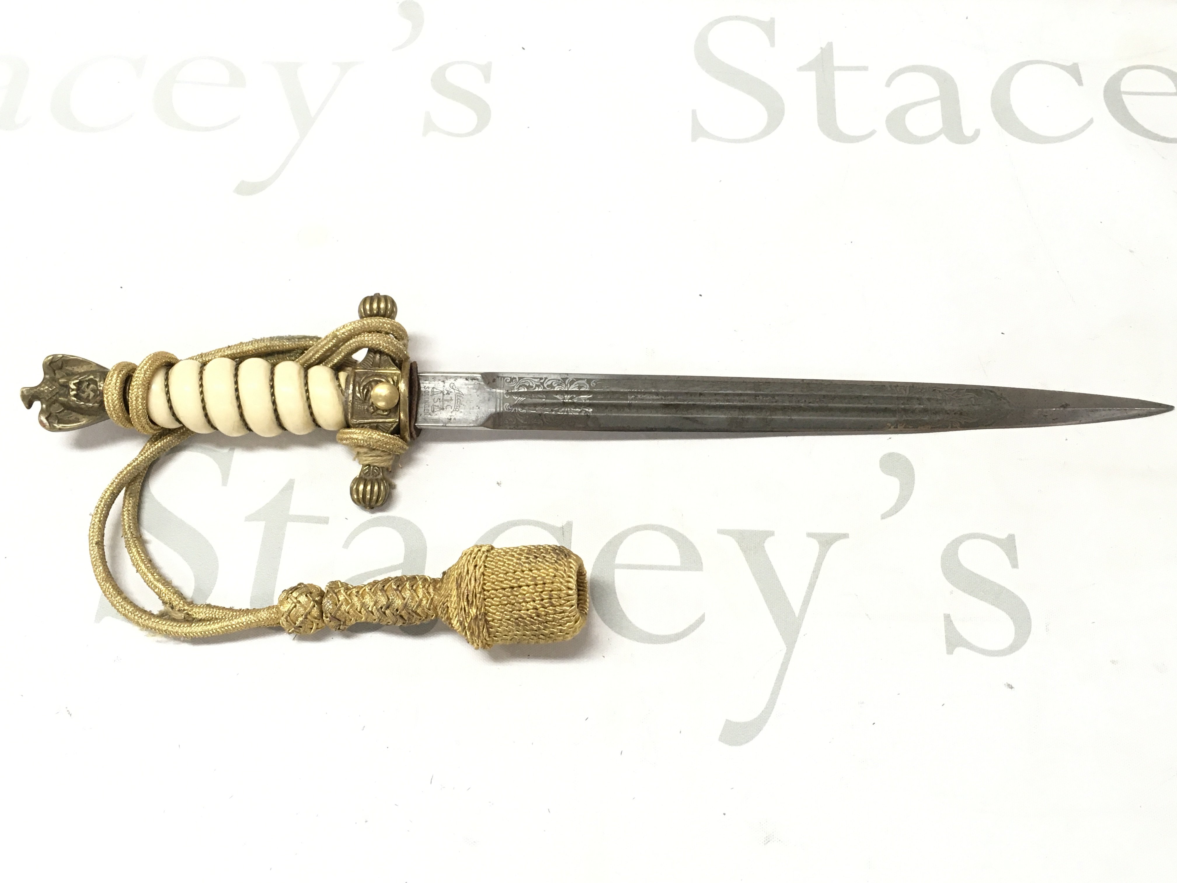 A WW2 Third Reich Kriegsmarine dagger by Alcoso with battle ship engraving on blade and gold sword knot. No scabbard. Blade 24cm long, 37cm long. This lot cannot be posted