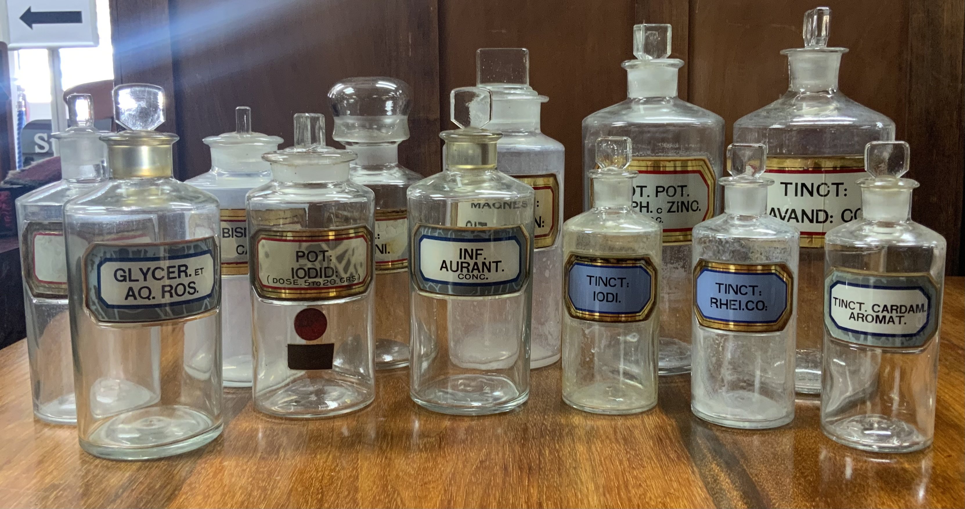 A collection early 20th century apothecary bottles and stoppers, each of cylindrical form with assorted faceted rectangular stopper and recessed labels. 16-24cm