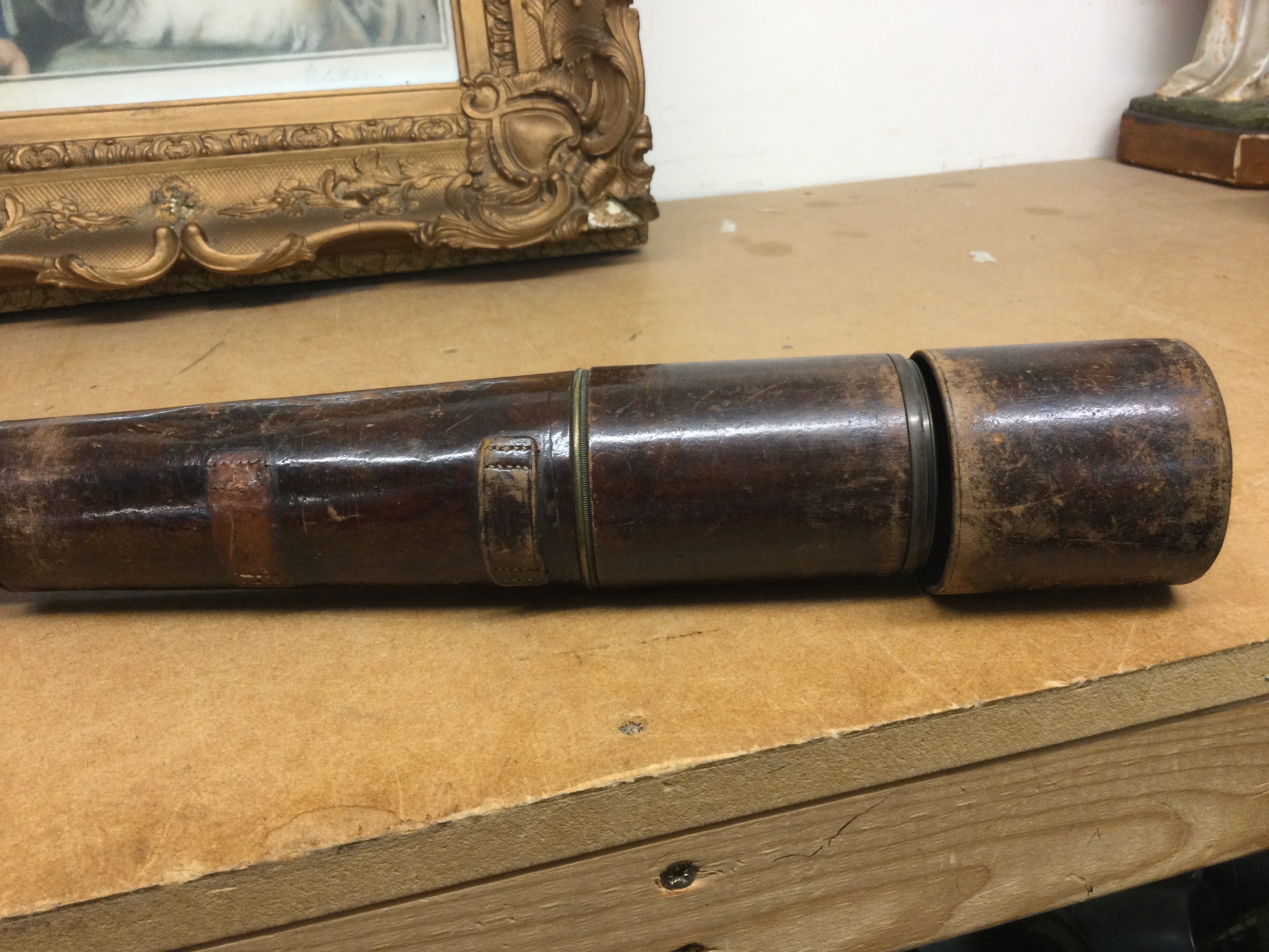 A three draw brass telescope with leather case .