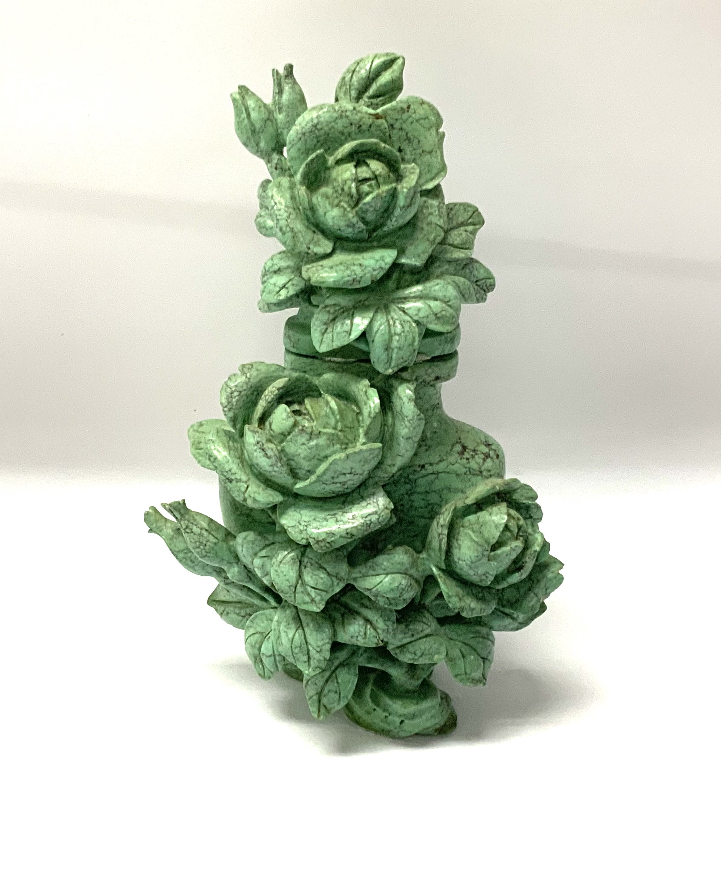 A small turquoise lidded vase with intricately carved rose bush decoration. 11cm.