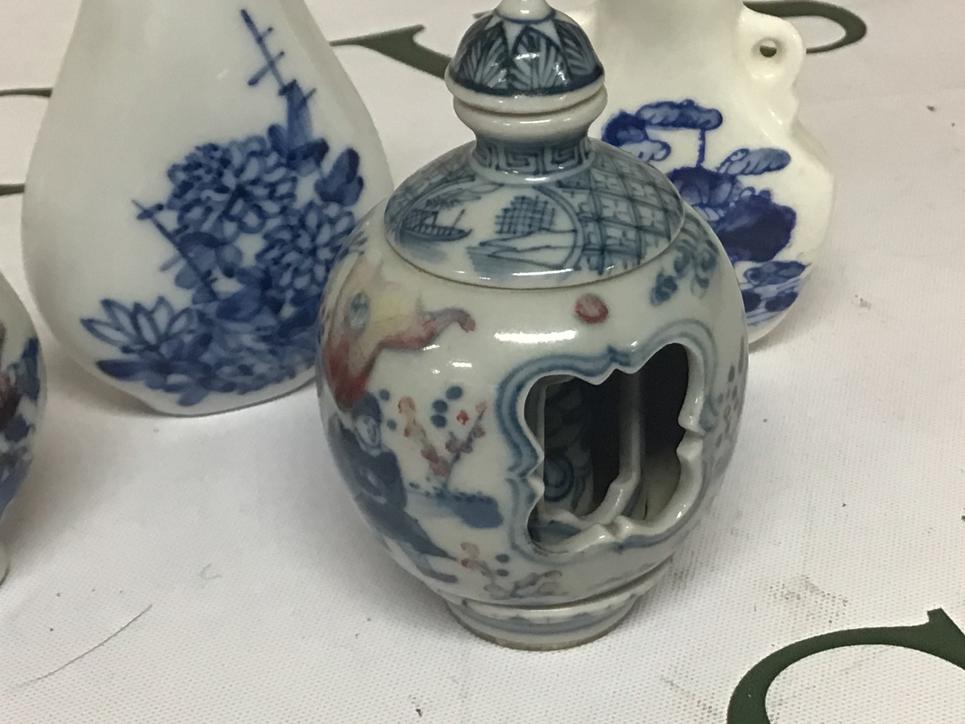 An interesting Chinese porcelain scent bottle with revolving central sections the sides decorated with figures and underglaze iron red with blue Caricature marks to the base and three other blue and white Chinese porcelain scent bottles. (4). NO RESERVE