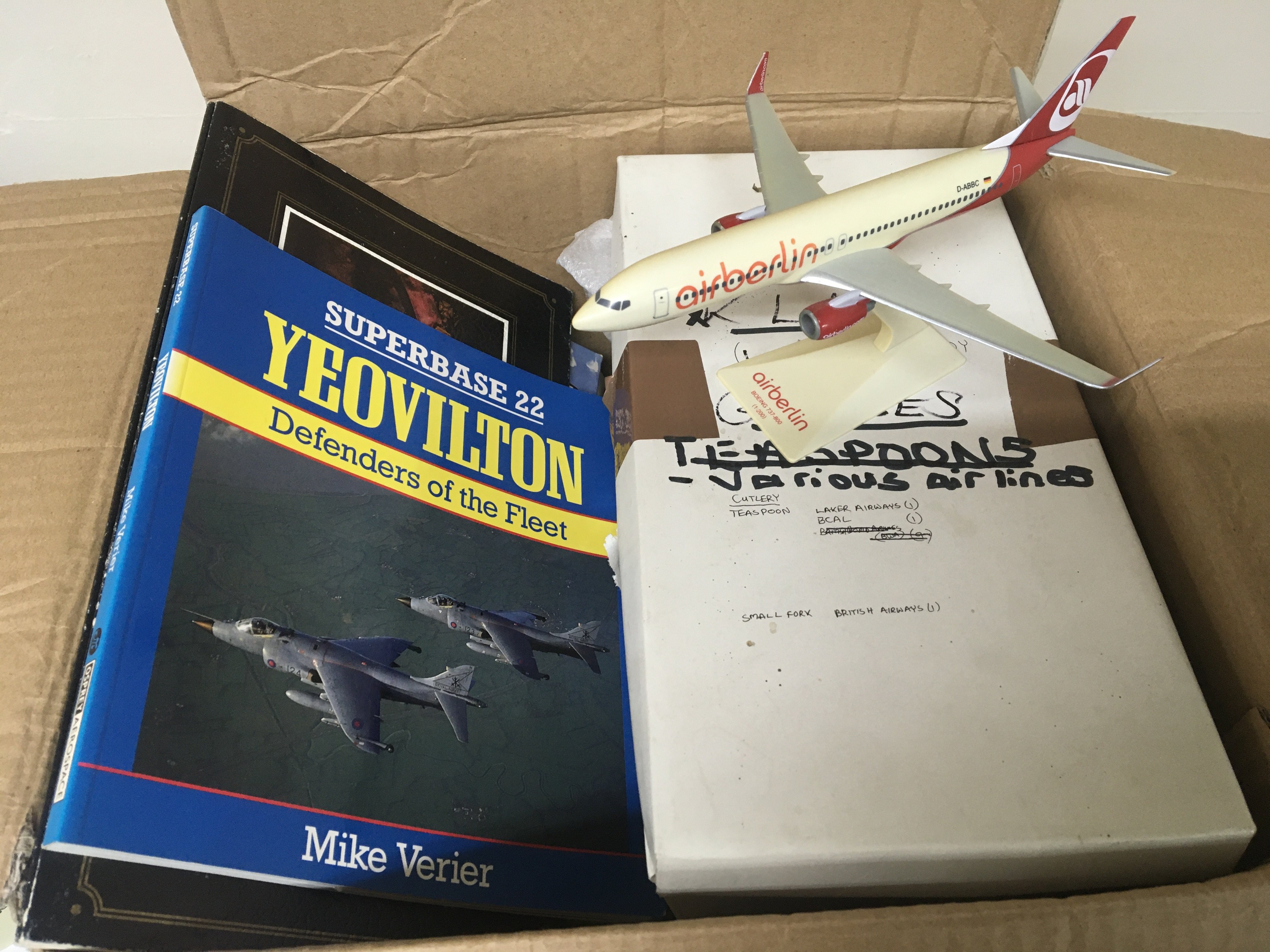 A box containing Aircraft memorabilia including books on U.K. airports commercial Airline glasses and cutlery an air Berlin model and other items.