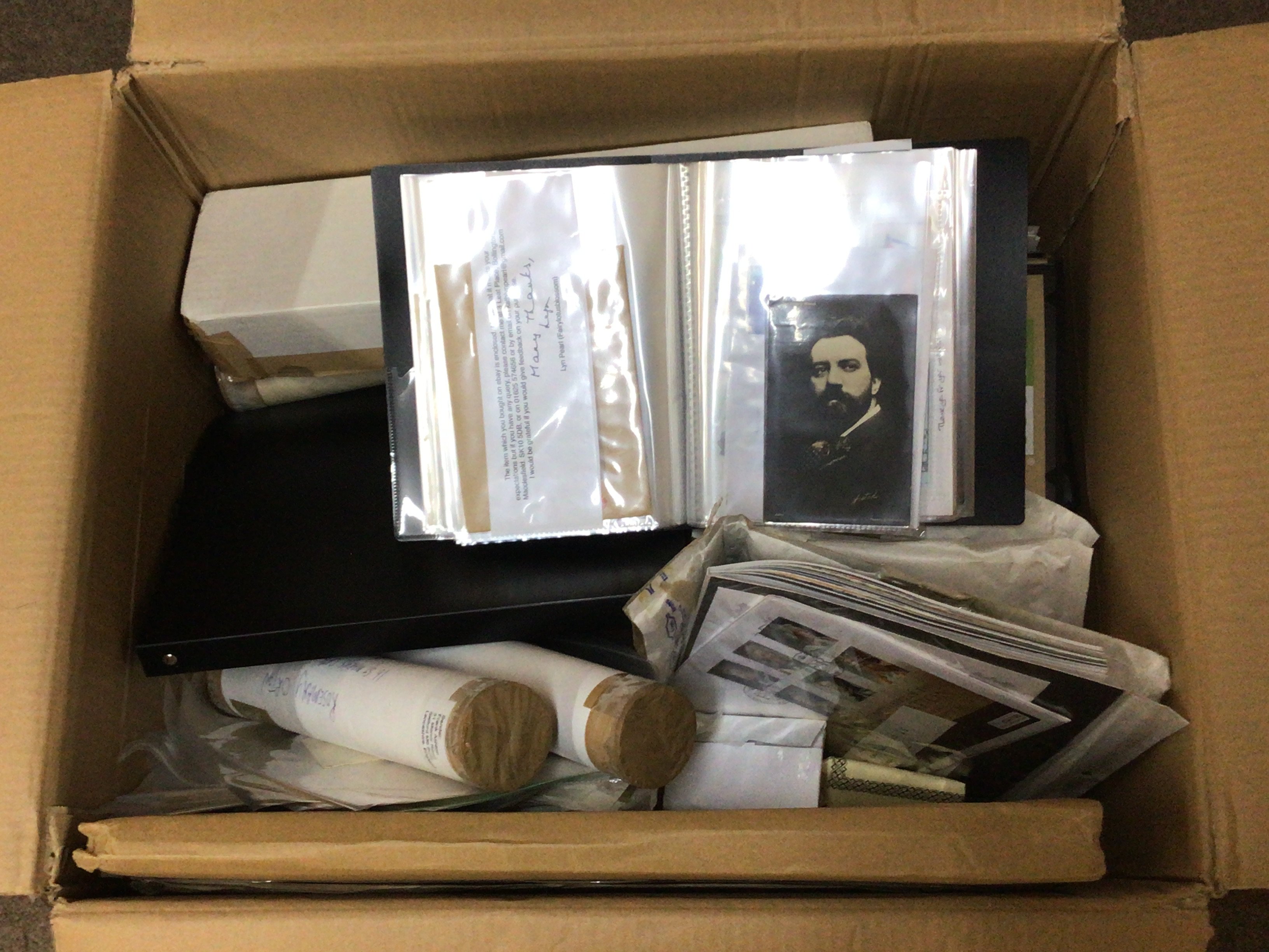 A box containing a collection of postcard albums posters prints and other ephemera.