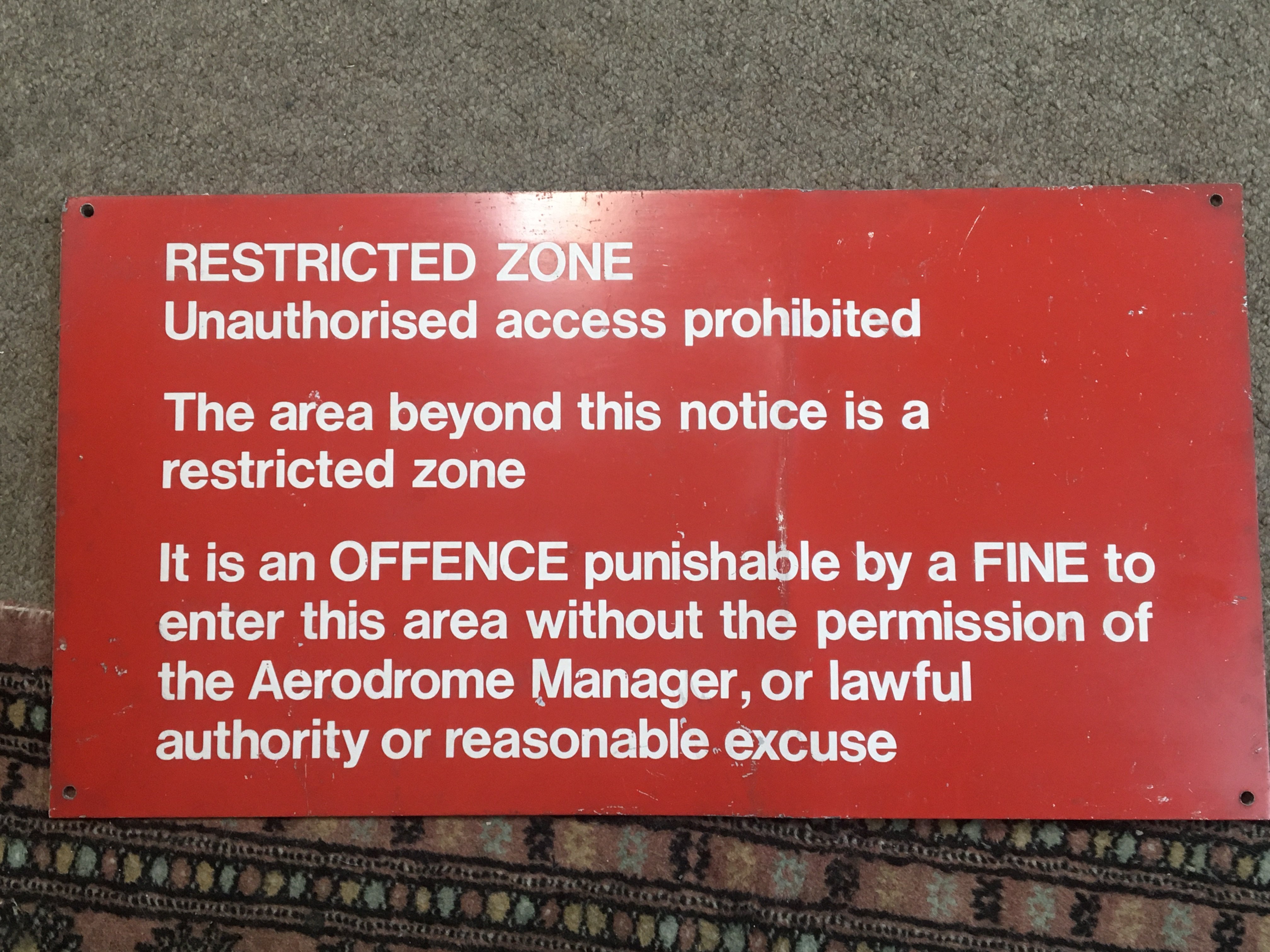 An Airport Restricted Zone sign 27cmx51cm red and white on aluminium.