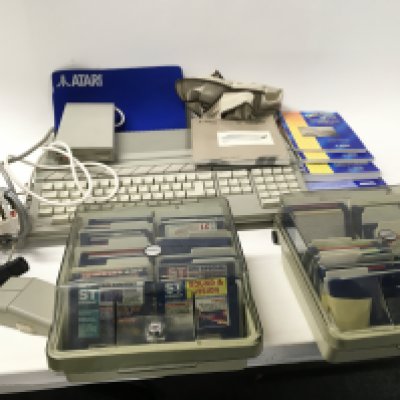 An Atari ST COMPUTER and accessories including floppy disk drive etc. includes two plastic disk storage boxes with floppy disk in. Also includes large box full with boxed games. (2)