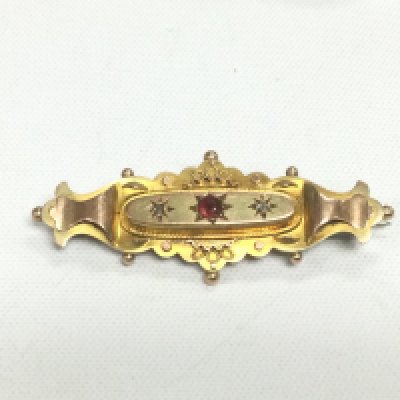 A 9ct gold brooch set with two small diamonds and a central ruby, approx 2.8g. Shipping category A.