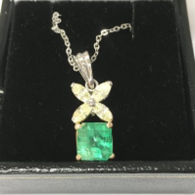 An 18ct white and yellow gold pendant set with square step cut emerald beneath 4 marquise cut diamonds on a silver chain. Emerald 1.25ct approx and 0.80ct diamonds approx. Postage B
