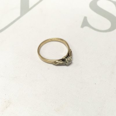 A gold solitaire ring with stone set shoulders.