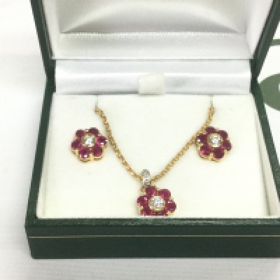 An 18ct gold, ruby and diamond daisy cluster pendant and earrings. Diamond colour G/H VS2/SiP. Shipping category A.