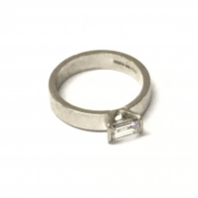 A platinum solitaire ring set with a rectangular cut diamond Approx 0.61cts. Approx weight 6.53 grams, size L.