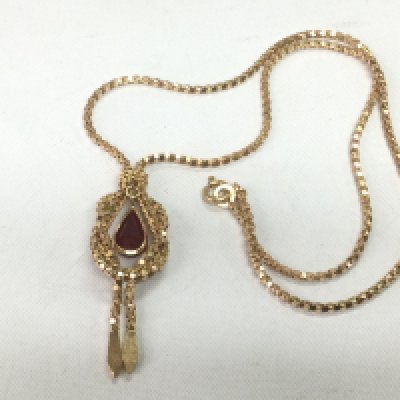A gold pendant and chain marked 750 but tested as 14k. Pendant set ith a ruby, approx 9.3g. Shipping category A.