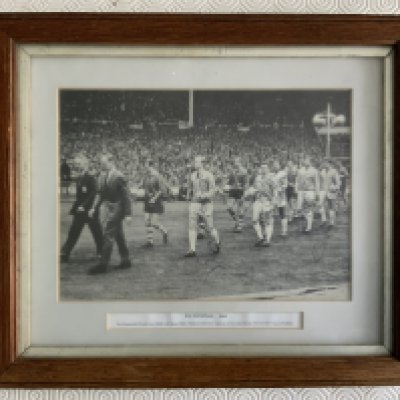 1964 West Ham Signed Framed Cup Final Picture: Great shot of Greenwood leading the teams out at Wembley with all 5 West Ham players having signed. Autographs of Greenwood, Moore, Byrne, Bovington, Bond and Hurst. Mounted and framed many years ago with genuine signatures. Measures just over 13 x 11 inches.