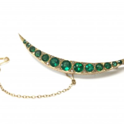 A 9ct gold Chester hallmarked crescent brooch set with small diamond shards and green sapphire. 4.8g total weight. Postage category A
