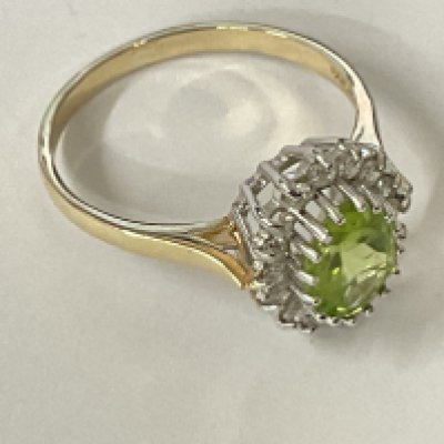 9ct yellow and white gold cluster ring set with an oval cut peridot and RBC diamonds. Ring size approx N/O. Postage category A.