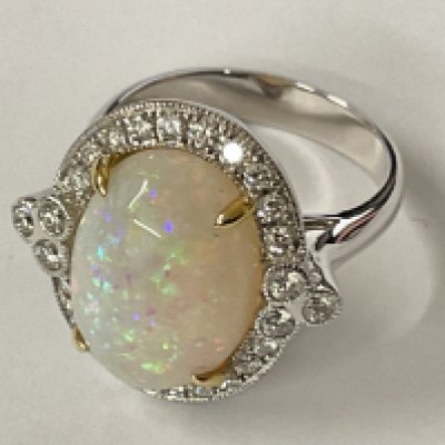 18ct white and yellow gold ring set with an oval cabochon Opal surrounded by RBC diamonds in a beaded setting. Opal 5.22ct. Diamonds 0.53ct. Ring size approx M/N. Postage category A.