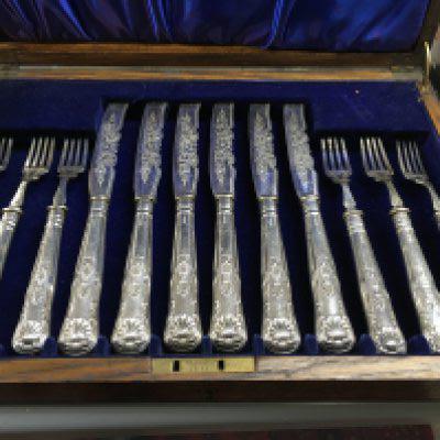 A oak case containing knifes and forks with silver handles.