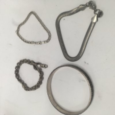 A silver bangle and three silver bracelets.