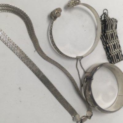 Two silver bangles a silver necklace and a silver gate bracelet.