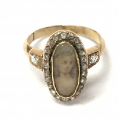 An antique gold ring set with an oval portrait with diamonds surround. 3.17g and size J Postage B