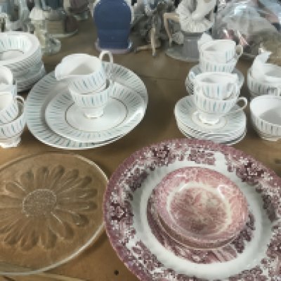 A Queen Ann tea set together with serving dishes in pink and a glass tray .