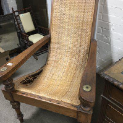 A Colonial reading chair with a woven wicker back and seat and hinged extending arm rests seat damaged. NO RESERVE