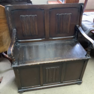 A small oak monks bench with linen fold decoration.