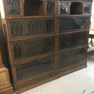 A pair of four tier oak lead light globe wernicke bookcases with single drawer to the base .