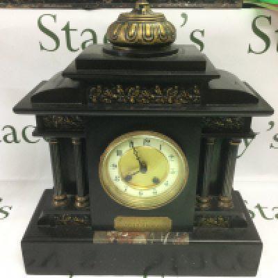A slate mantle clock with decorative panels and Corinthian column supports. Shipping category D.