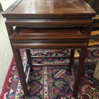 A nest of two mahogany occasional tables .