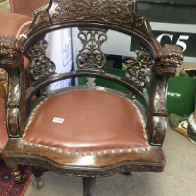 A Chinese office swivel chair carved with dragon heads flowers and foliage.