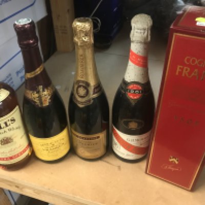 A box containing wines and sprites including cognac and bells whisky .