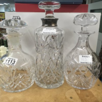 A glass detector with silver rim and two glass decanters.