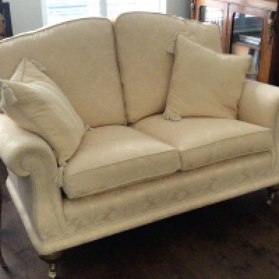 A fine quality two seater sofa upholstered in yellow floral fabric with two scatter cushions on mahogany legs terminating with brass caps and casters. (Sold in situ delivery arrangements by appointment)