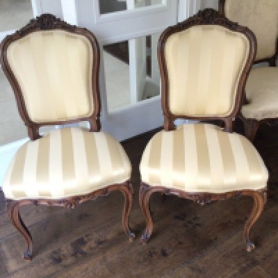 A pair of conforming French Louis XVI style matching chairs with carved top rail tastefully upholstered in quality yellow striped fabric carved top rails and cabriole legs.
