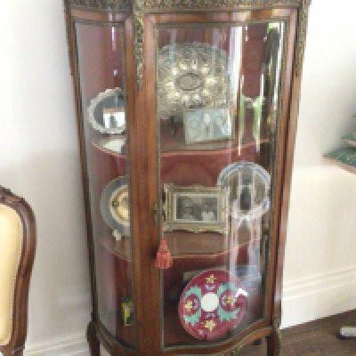 A French late 19th century walnut display cabinet with gilt metal mounts and serpentine glass door enclosing shelves.