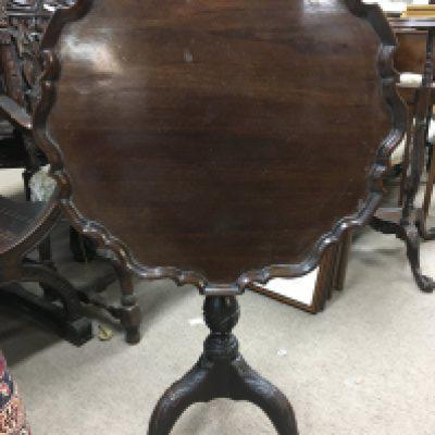 A George 111 carved Mahogany occasion table the tip action top with a shaped edge on a spiral column with a ring Of repeat pattern flowers the cabriole legs with carved Knuckles terminating in ball and claw feet 57 cm Height 69 cm .